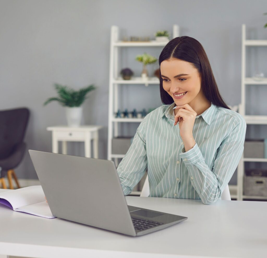 Profissional de saúde em consulta por vídeo no notebook, usando fones de ouvido, em ambiente claro.